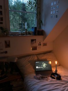 an open laptop computer sitting on top of a bed next to a window in a bedroom