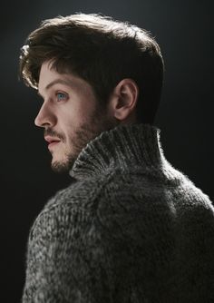 a man with blue eyes wearing a gray sweater