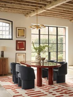 a dining room table with four chairs and a rug on the floor in front of it