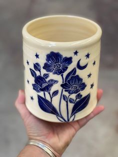 a hand holding a blue and white flower pot