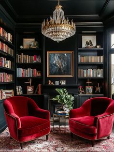 a living room with two red chairs and a chandelier