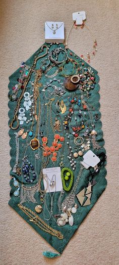 a green piece of cloth covered in lots of jewelry