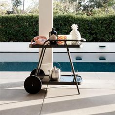 an outdoor bbq with food and drinks on the table next to a swimming pool