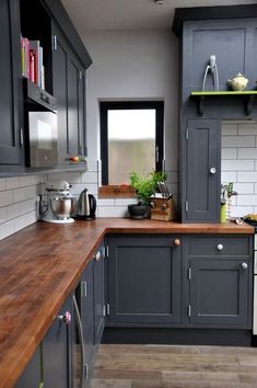 a kitchen with gray cabinets and wooden counter tops