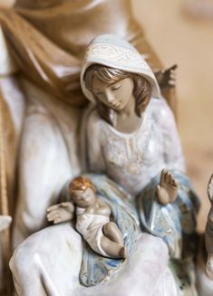 a figurine of a woman holding a baby in her lap and sitting on a chair