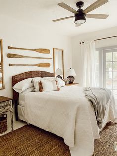 a bed sitting in a bedroom next to a window with a fan on top of it