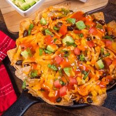 nachos with cheese, black beans and avocado on a cutting board