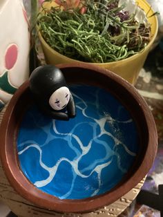 a small black and white cat figurine sitting on top of a blue bowl