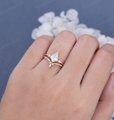 a woman's hand with a ring on it and white flowers in the background