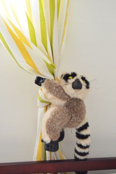 a stuffed raccoon is holding onto some yellow and white striped paper streamers