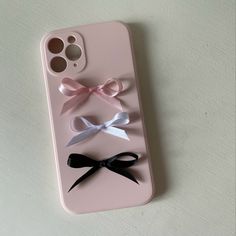 an iphone case with three different bows on the front and back cover, sitting on a white surface