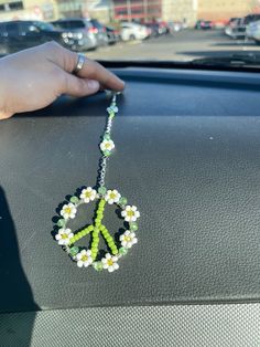 a peace sign beaded with daisies on a car dashboard