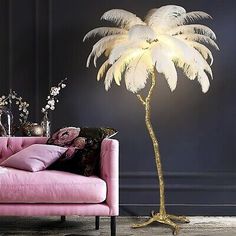 a living room with a pink couch and a palm tree lamp on the floor next to it