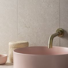 a bathroom sink with a gold faucet next to it and a pink bowl