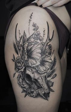 a woman's thigh with flowers on it and a cow skull in the middle