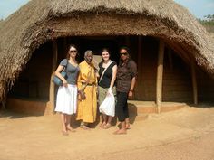 three women standing in front of a hut