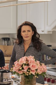 two women standing in a kitchen next to a table with food and flowers on it