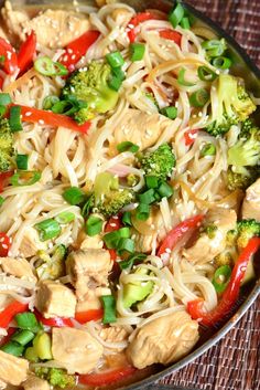 a pan filled with noodles, broccoli and peppers