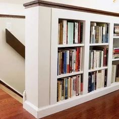 a bookshelf filled with lots of books on top of a hard wood floor