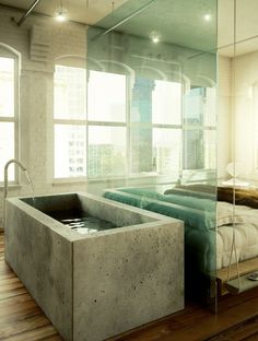 a bathtub in the middle of a room with a bed and window behind it