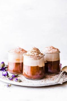 three desserts on a plate with spoon and flowers