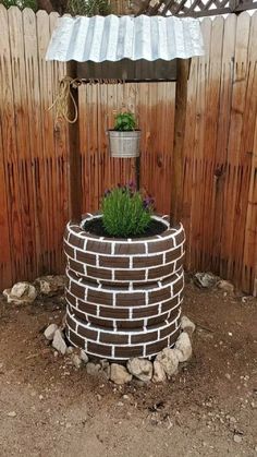 a brick planter with a potted plant in it on the side of a fence