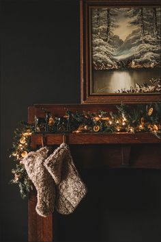 christmas stockings hanging from a mantle with lights on it and a painting in the background