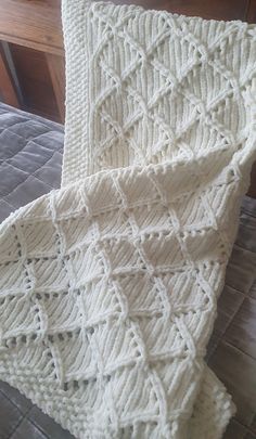 a white crocheted blanket sitting on top of a bed