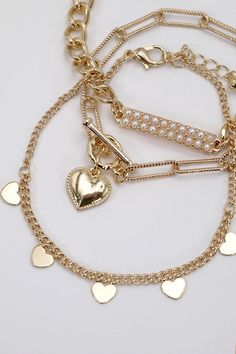 Pearl Stud Bar Heart Link Multi-Chain Bracelet Set, a captivating ensemble that beautifully combines classic pearls, modern bar details, and heart-shaped links for a unique and stylish accessory. Pearl Stud Accents: Each bracelet in this set features lustrous pearl studs. The heart-shaped links connect the various chains, infusing the bracelets with a romantic and charming vibe. The heart links serve as focal points, adding sentiment and sweetness to the overall aesthetic.DIMENSION length: 8" ex Gold Heart Beads Bracelet For Party, Elegant Pearl Heart Bracelet With Charm, Heart Shaped Pearl Bracelet, Gold Elegant Heart Beads Bracelet, Elegant Gold Heart Beads Bracelet, Multi Chain Bracelet, Gold Bracelet Set, Sunglass Chain, Focal Points