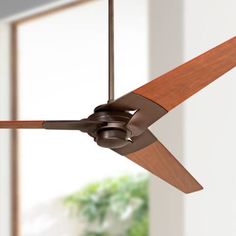 a ceiling fan with wooden blades in an empty living room, showing the light fixture