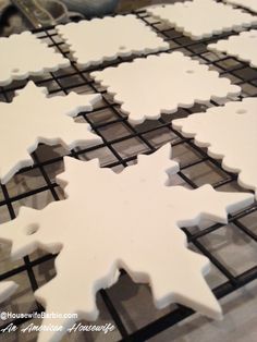 several white snowflake cookies are on a cooling rack, ready to be baked