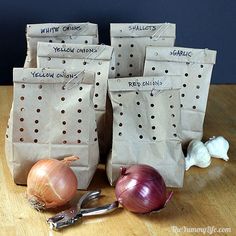 some onions and garlic sitting on a table next to two bags with writing on them