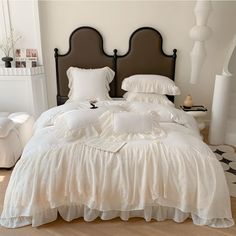 a bed with white ruffled bedspread and pillows