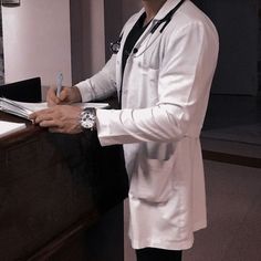 a man in a white lab coat writing on a piece of paper at a desk