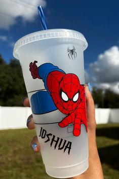 a person holding up a plastic cup with spiderman on it