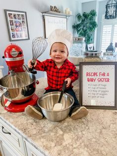 a baby sitting on top of a kitchen counter next to a bowl and whisk