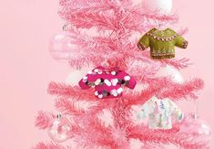 a pink christmas tree with ornaments on it and an ornament hanging from the top