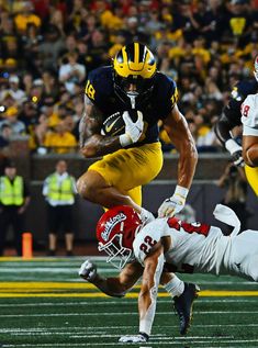 a football player running with the ball in his hand and another person diving for it