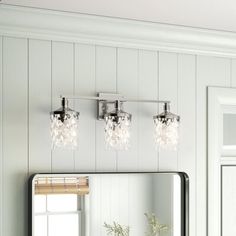 a bathroom vanity with three lights and a mirror on the wall next to a window