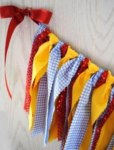 a bunch of different colored ties hanging on a wall with a red ribbon around them