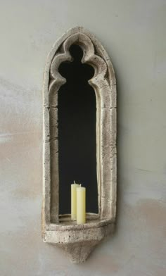 a candle that is sitting in front of a mirror on the side of a wall