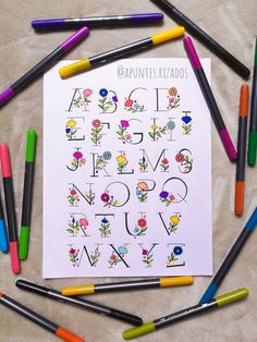 a sheet of paper with letters and flowers on it surrounded by colored crayons