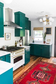 a kitchen with green cabinets and an area rug on the floor in front of the stove