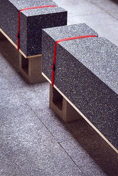 two concrete benches with red ribbon on them sitting in the middle of a floored area