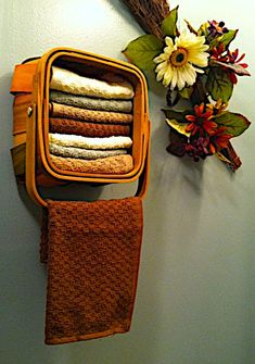 an orange towel hanging on the wall next to a bunch of folded towels and flowers