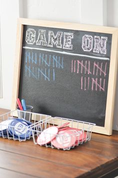 a chalkboard with game on written on it next to some cups and pencils