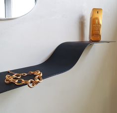 a black shelf with a gold chain hanging from it's side next to a mirror