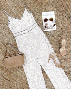 a white dress and shoes are laying on the floor next to a purse, handbag, and magazine