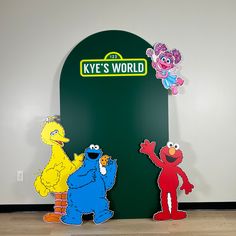 three sesame street characters standing in front of a key's world sign and door