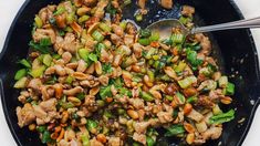 a skillet filled with stir fry vegetables and meat on top of a white table